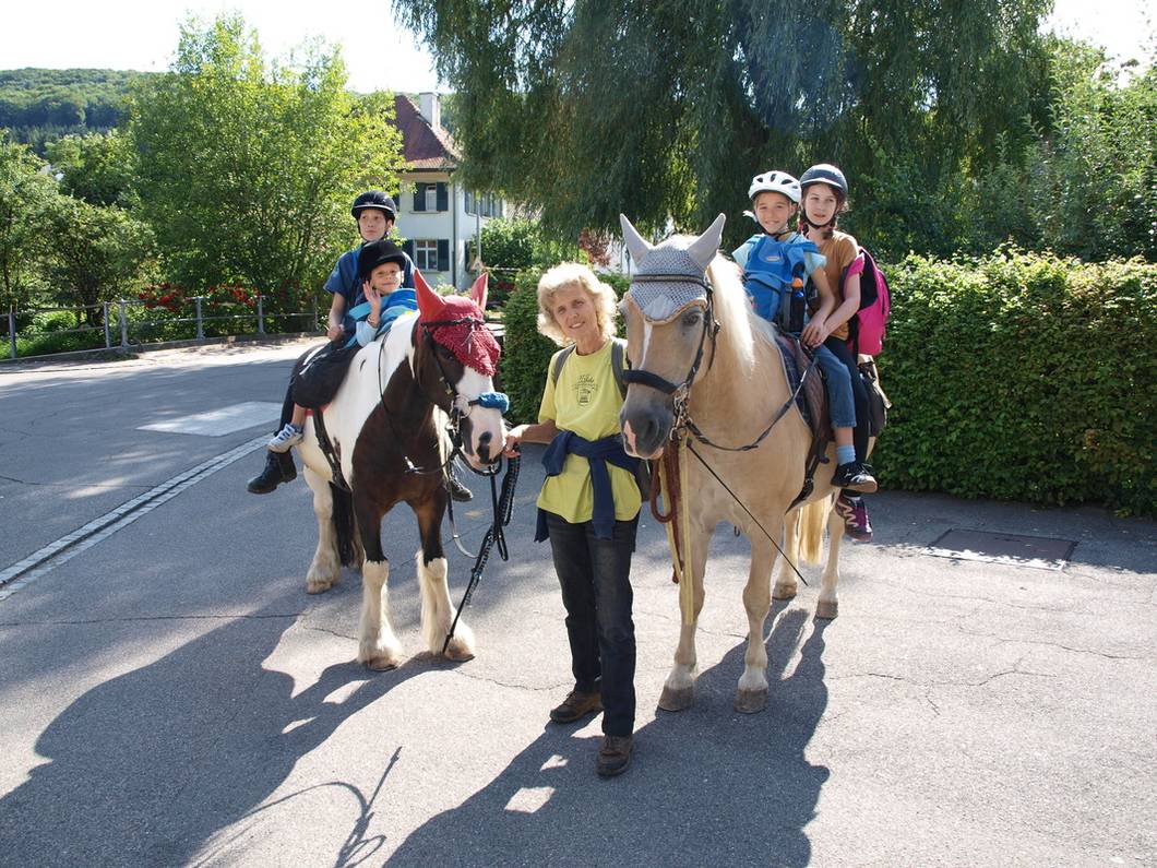 Eine Reitgruppe mit Kindern unterwegs im Dorf